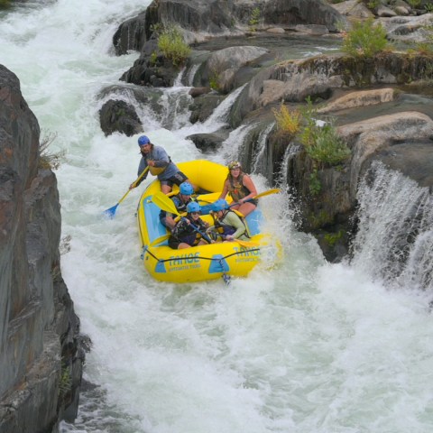 People whitewater rafting in a narrow rocky gorge.