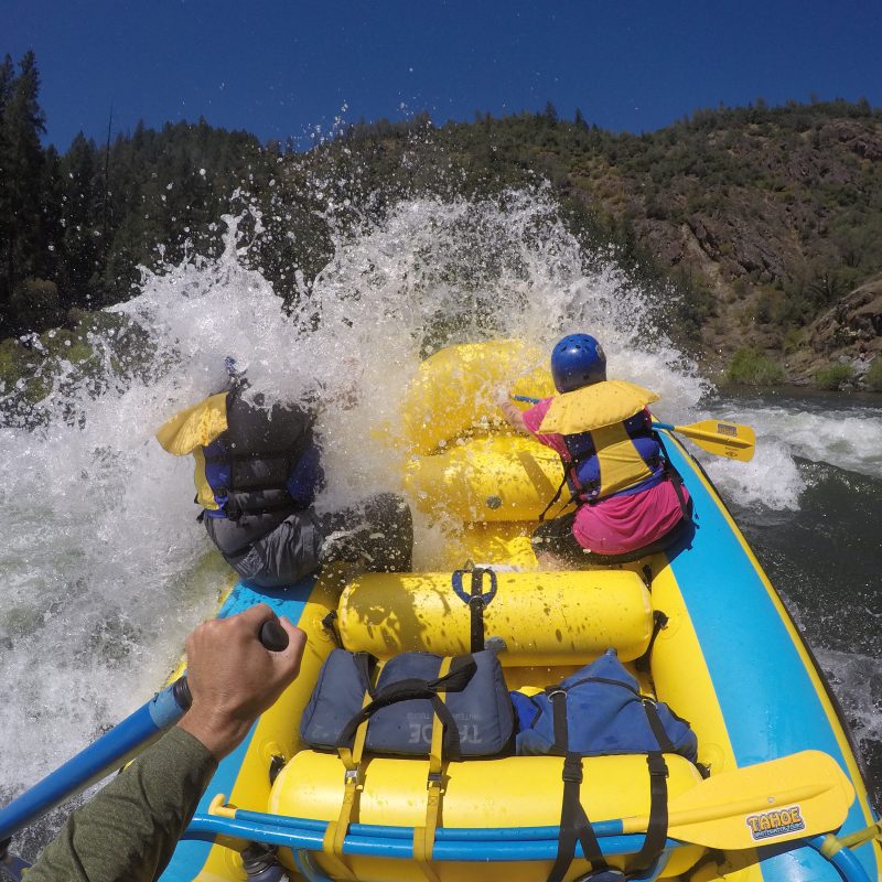 People in a yellow raft navigating white-water rapids.