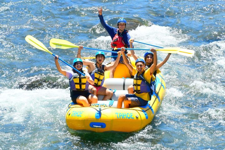 a man riding a surfboard on a raft in a body of water