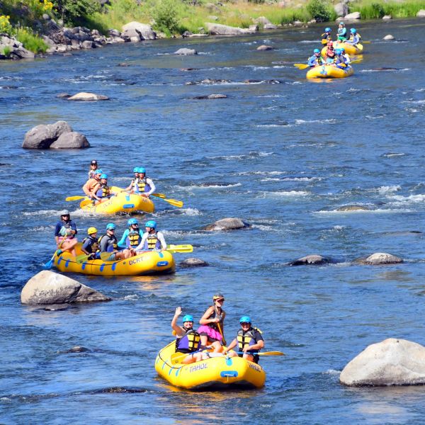 People rafting in yellow boats down a river with rocks and clear water.