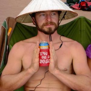 a man wearing a hat sitting on a bed