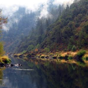 a large waterfall over a body of water with a mountain in the background